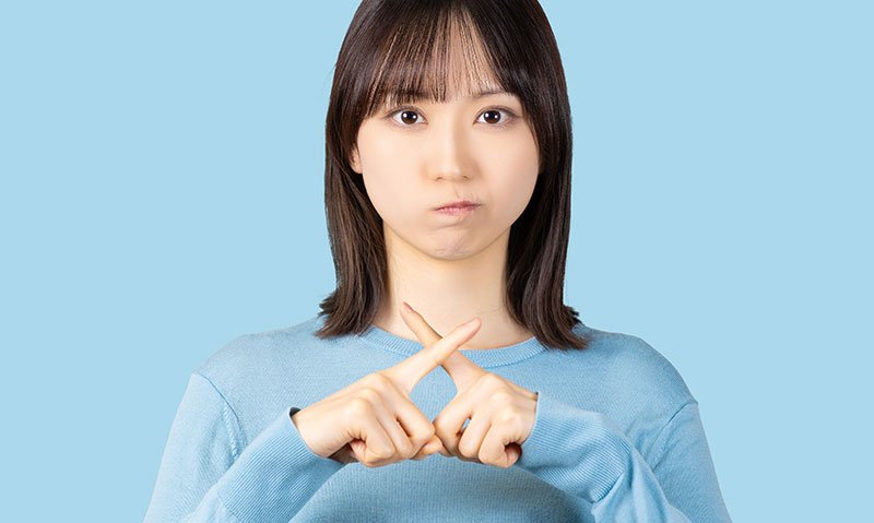 指でバツを示す女性
